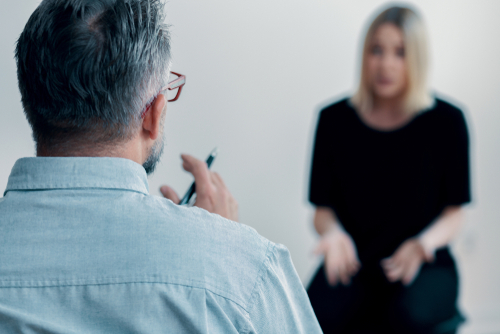 therapist holding a pen talking to his blurred female patient 2