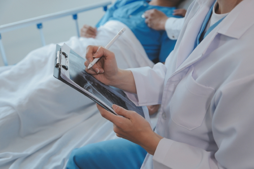 Injured patient showing doctor broken wrist and arm with bandage in hospital office or emergency room