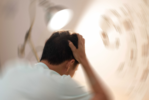 Man hands on his head felling headache dizzy sense of spinning dizziness,a problem with the inner ear, brain, or sensory nerve pathway