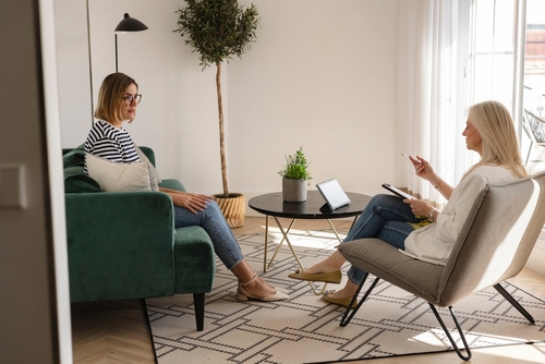 Psychologist taking notes while listening to her patient talking about her mental health problems