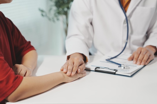 This clinical image depicts a physician performing a physical examination using a stethoscope to listen to the patient's heartbeat or lung sounds